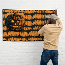 Load image into Gallery viewer, Person hanging a Halloween-themed wall art featuring a jack-o'-lantern on a white brick wall.